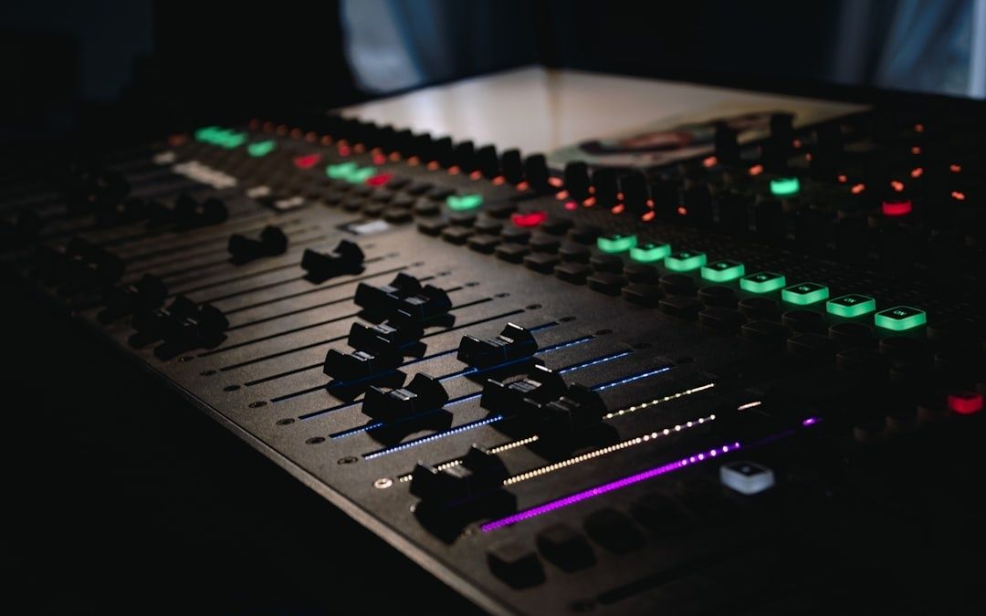 Nahaufnahme eines beleuchteten analogen Audiomischpults im dunklen Studio
