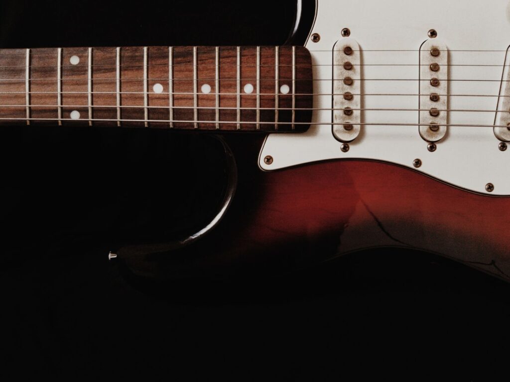 Nahaufnahme einer E-Gitarre mit Griffbrett, Saiten und Tonabnehmern